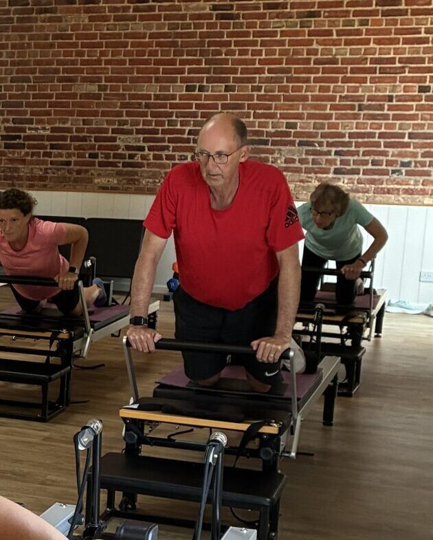 A man in his seventies kneels on a reformer bed during a class at Cottesloe Physio, Wing